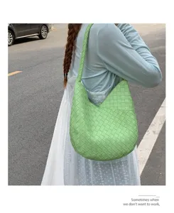 Detailed close-up of the light green woven shoulder bag, highlighting exquisite craft and texture.