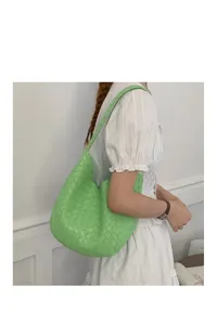 Detail shot of green woven shoulder hobo bag for women, stylish minimalist daily commute style.