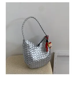 Silver woven shoulder bag for women, stylish hobo bucket bag with trendy charm for daily commute.