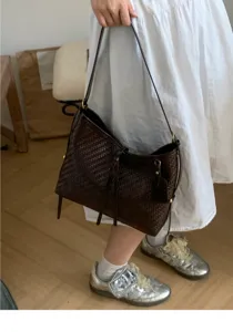 Detail view of a vintage dark brown woven leather bucket shoulder bag with elegant metal hardware.