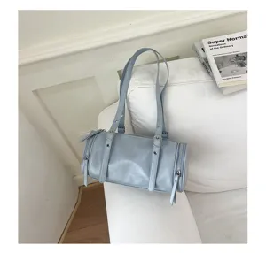 Detalle de bolso de hombro cilíndrico azul claro, diseño de bolso minimalista.