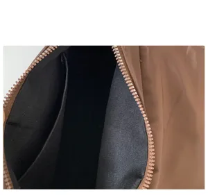 Detailed close-up of brown nylon women shoulder bag interior zipper and black lining.