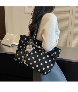 Black polka dot suede tote bag detail view, casual shoulder bag with floral pendant.