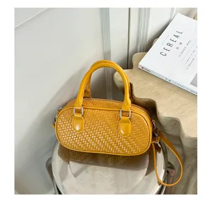Close-up of a stylish yellow woven texture handbag displayed on a modern metallic stool.