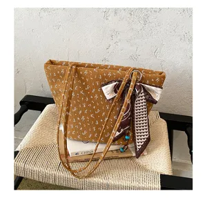 Gedetailleerd shot van retro bloemrijk corduroy schoudertas tote met zijden sjaal.