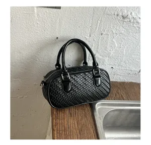 Black woven texture handbag detail close-up showing fine craftsmanship and retro metal hardware.