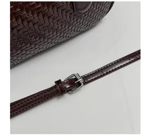 Woven leather shoulder bag detail with adjustable metal buckle and dark brown texture.