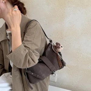 Retro braune Wildleder Umhängetasche für Damen, elegante Vintage Achseltasche mit Bärenanhang.