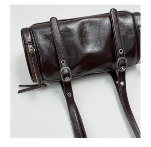 Detalle de bolso de hombro cilíndrico marrón oscuro retro, elegante bolso tipo almohada.
