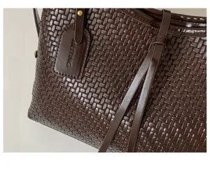 Close up of dark brown woven leather shoulder bag showing texture and tag detail.