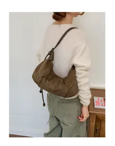 Detail view of brown suede hobo dumpling bag with shoulder strap and stylish drawstring.