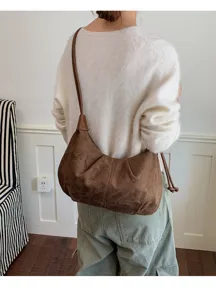 Brown suede underarm bag detail shot showcasing soft fabric texture and curved design.