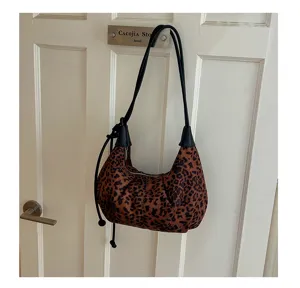 Detailed view of vintage leopard print suede shoulder hobo bag hanging on white door.