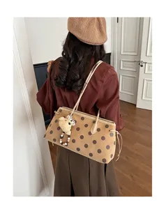 Brown polka dot suede shoulder bag detail view, chic commuting handbag with cute bear charm.