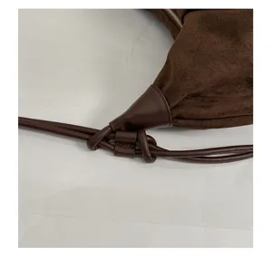 Brown suede shoulder bag closeup detail showcasing elegant leather knot accent and texture