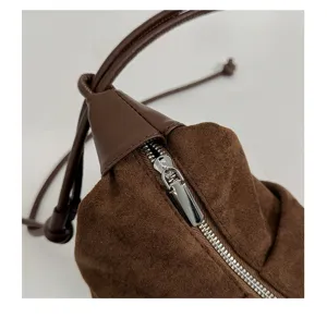 Close-up detail of brown suede shoulder bag zipper, minimalist leather strap design.