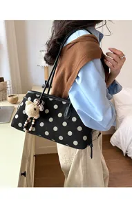 Black suede shoulder bag with white polka dots, stylish underarm bag detail view.