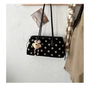 Detailed view of the black polka dot suede shoulder bag with cute bear pendant and fine straps.
