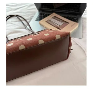 Brown suede shoulder bag detail, large polka dot pattern, elegant commuting handbag close-up
