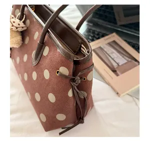 Detail shot of brown suede polka dot shoulder bag with leather handles and drawstring design.