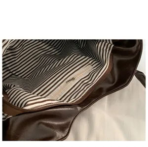 Detailed interior view of the brown leather shoulder bag with striped lining and zipper pocket.