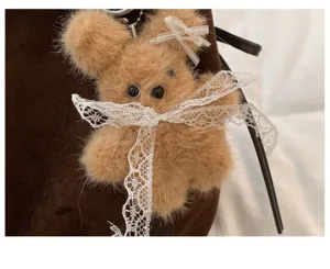 Fluffy brown bear plush keychain detail with elegant lace bow for stylish handbag decoration.
