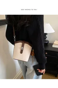 Dettaglio borsa a secchiello elegante con design bicolore e chiusura in metallo.