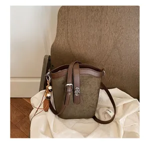 Primo piano della borsa a secchiello verde opaco con tessuto strutturato e chiusura metallica.