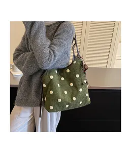 Retro green suede shoulder bag detail showing fluffy white polka dots and stylish strap.
