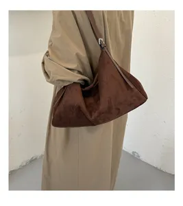 Détail de sac porté épaule en suédine marron, design souple sous les aisselles avec sangle.