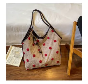 Detailed view of the vintage suede plush tote bag with red polka dots and leather straps.