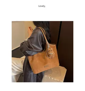Retro brown suede shoulder tote bag detail showcasing large capacity and cute bear pendant.
