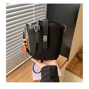 Vista dettagliata della borsa a secchiello nera opaca, con design minimalista e chiusura in metallo.