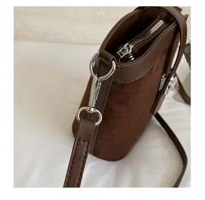 Primo piano dettagliato della borsa secchiello in camoscio marrone scuro con metalleria.