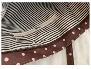 Detalle interior del bolso tote de lona con bolsillo con cremallera y forro a rayas.