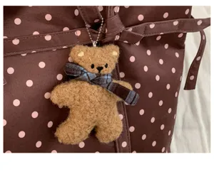 Detalle de llavero de oso de peluche lindo en bolso tote de lona de lunares para uso diario.