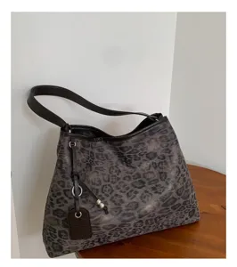 Primer plano detallado del bolso de hombro con estampado de leopardo vintage, correa y etiqueta.