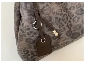 Detalle de bolso tote vintage con estampado de leopardo, tela texturizada y correa.