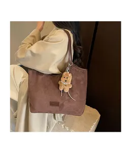 Detail shot of retro brown suede tote bag with cute plush dog pendant and shoulder strap.