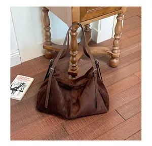 Détail de sac bandoulière en suédine marron, texture douce visible, style minimaliste chic.
