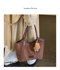 Retro brown suede tote bag detail shot showing plush bear charm and textured fabric.