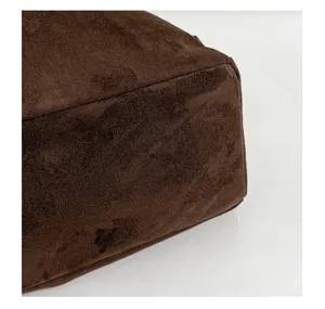 Gros plan détaillé de la texture en daim marron doux et des coutures soignées d'un sac pour femme.
