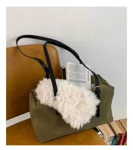 Detailed view of the large capacity green suede shoulder bag with plush accessory and black straps.