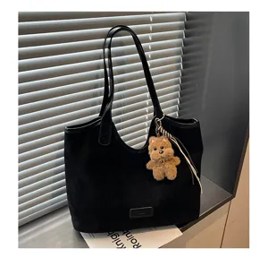 Detailed view of black suede tote shoulder bag with cute bear charm and large capacity.