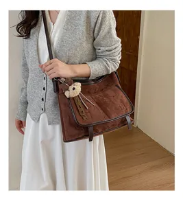 Brown suede shoulder bag detail, soft fabric crossbody purse with cute bear pendant charm.