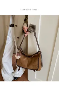 Detailed view of women autumn brown suede shoulder hobo bag with cute bear pendant.