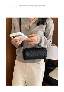 Detailed shot of a black woven cylindrical shoulder bag worn by model, showing texture.