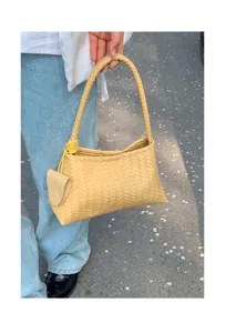 Detailed view of yellow woven leather shoulder bag, chic underarm bag design for daily wear.