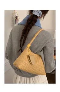 Woven shoulder bag detail view, chic yellow leather underarm purse with stylish braided design.