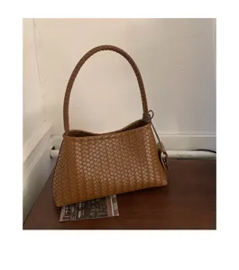 Detailed shot of brown woven leather shoulder bag, elegant intrecciato design for daily use.